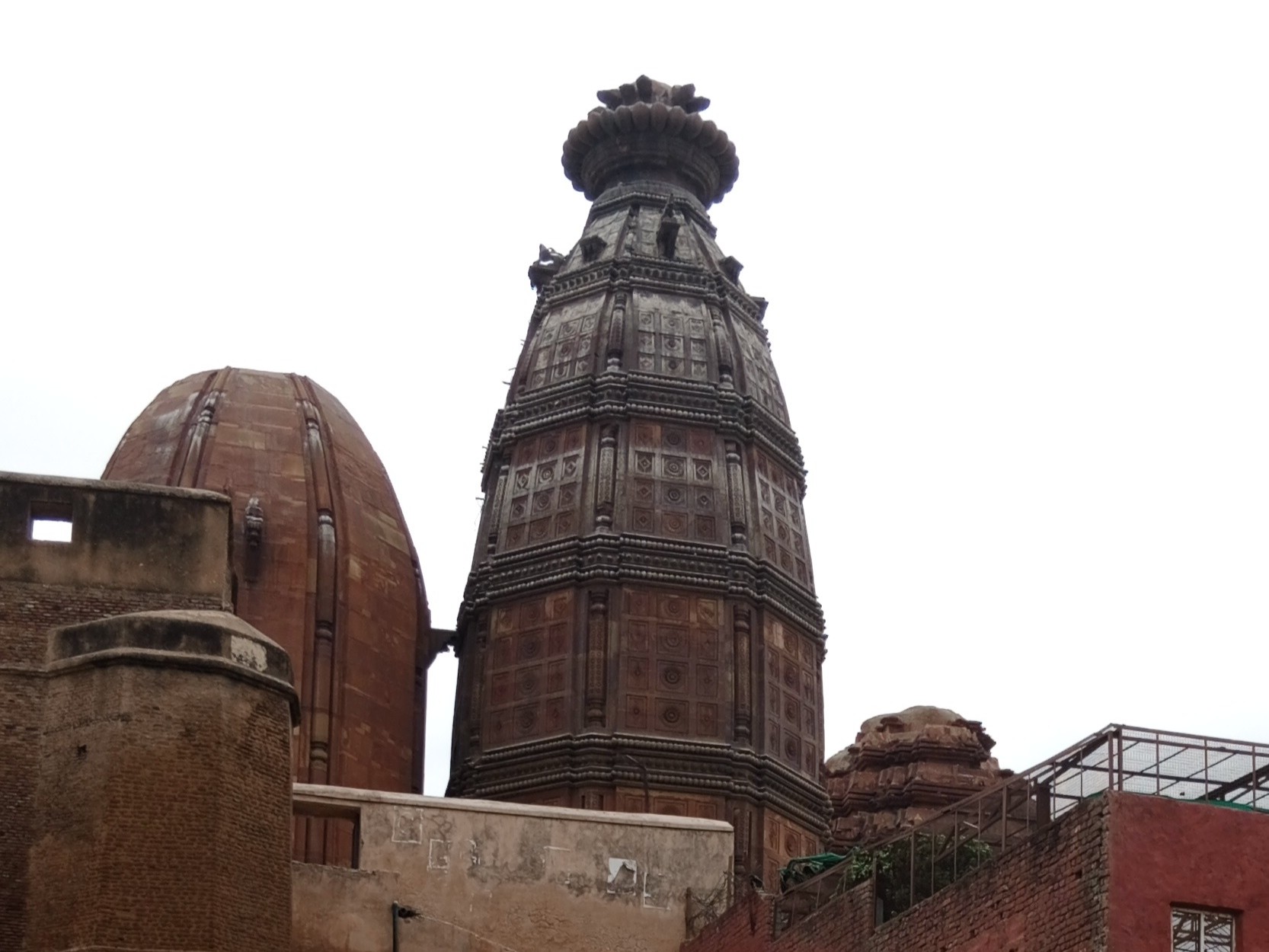 The tall carved stone tower of Madan Mohan Mandir rising above the temple's older domed shrines